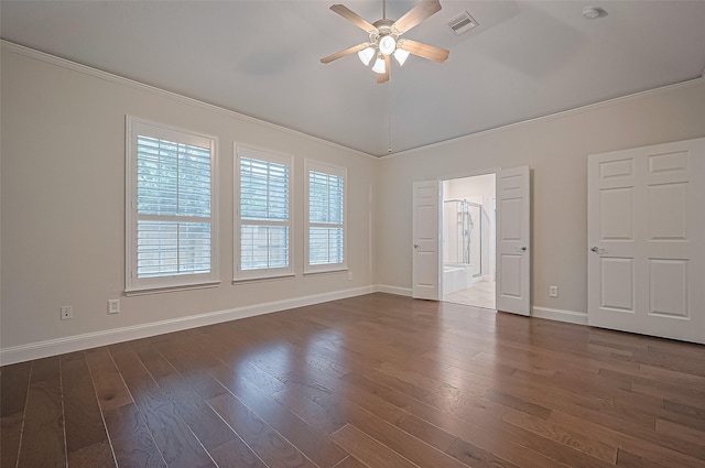 empty room with crown molding, ceiling fan, baseboards, dark wood-type flooring, and vaulted ceiling