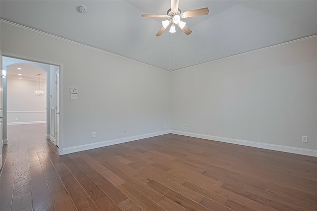 spare room featuring dark wood-style flooring, baseboards, ornamental molding, and ceiling fan with notable chandelier