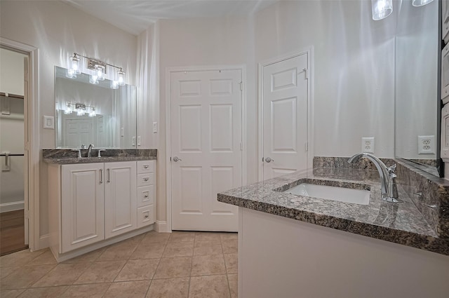 bathroom featuring two vanities, a sink, tile patterned flooring, and a closet