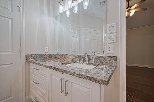 bathroom with visible vents, vanity, wood finished floors, baseboards, and ceiling fan