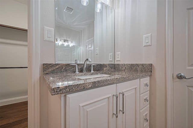 bathroom featuring visible vents, baseboards, wood finished floors, and vanity