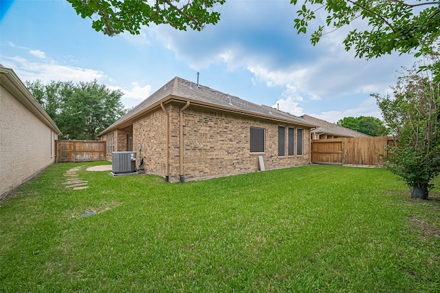 rear view of property with brick siding, a fenced backyard, and a lawn