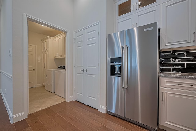 kitchen featuring wood finished floors, washer and dryer, glass insert cabinets, white cabinets, and high end refrigerator