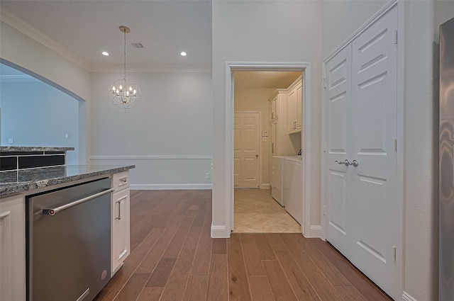 kitchen featuring washing machine and clothes dryer, stainless steel dishwasher, dark wood finished floors, dark stone counters, and white cabinetry