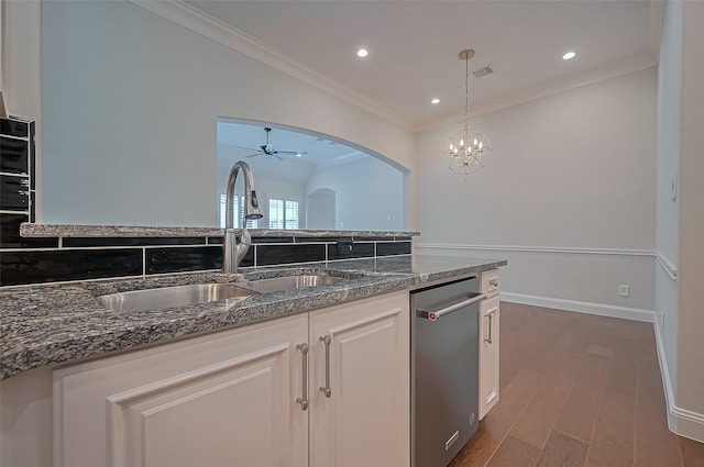 kitchen with wood finished floors, dishwasher, a sink, dark stone counters, and ornamental molding