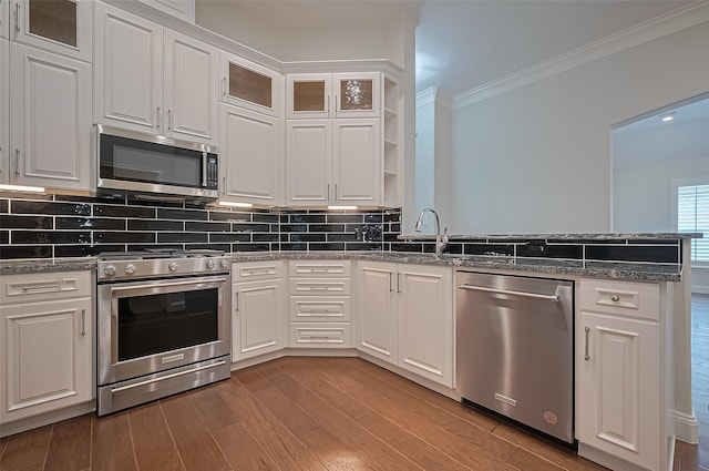 kitchen featuring crown molding, appliances with stainless steel finishes, a sink, a peninsula, and white cabinetry