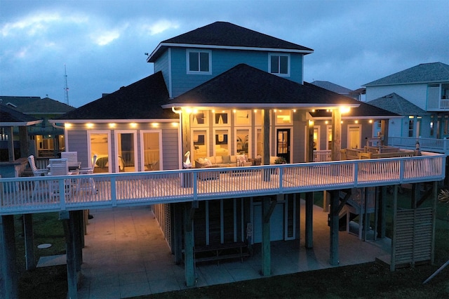 rear view of property featuring a patio, roof with shingles, and a wooden deck