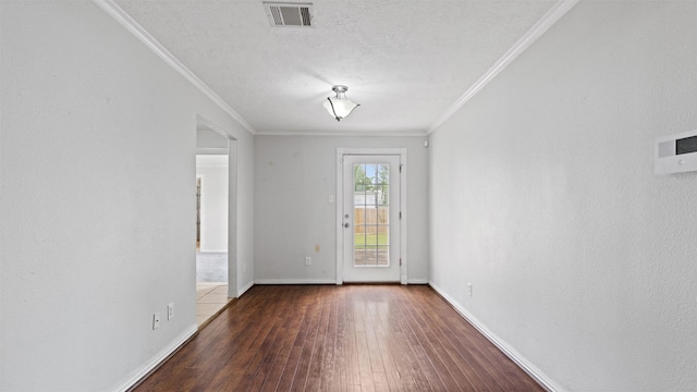 empty room featuring crown molding, wood-type flooring, a textured ceiling, baseboards, and visible vents