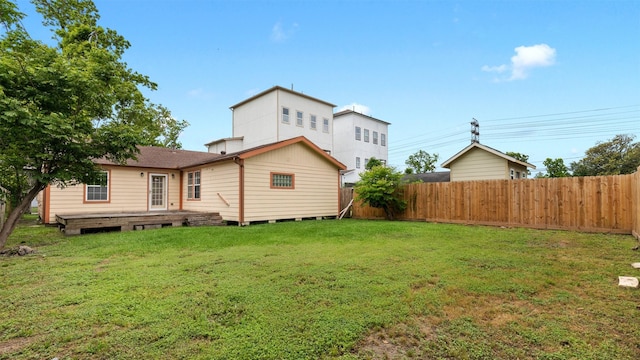 rear view of house with a yard, a deck, and fence