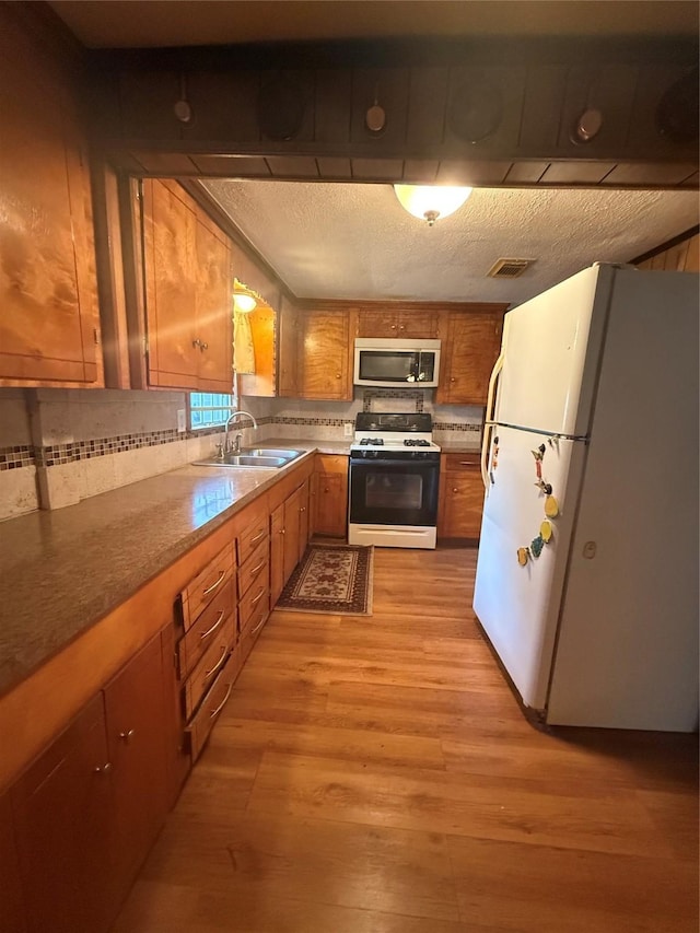 4300 Weaver Rd, Houston, TX 77016 - kitchen with brown cabinetry, freestanding refrigerator, gas range oven, stainless steel microwave, and a sink