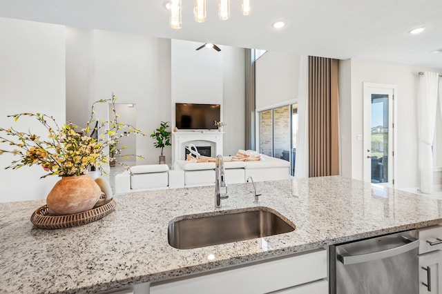 453 Stratus View Ct, Katy, TX 77493 - kitchen featuring white cabinets, light stone counters, a sink, a fireplace, and stainless steel dishwasher