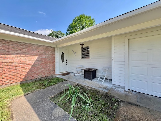 view of exterior entry with brick siding and a garage
