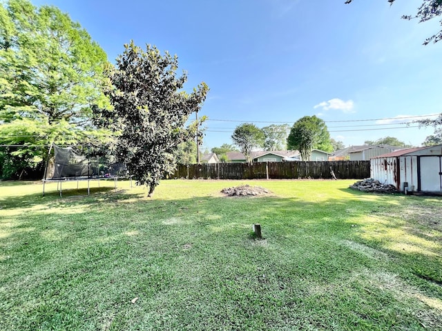 view of yard featuring a storage shed, a trampoline, an outdoor structure, and a fenced backyard