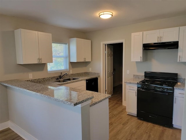 kitchen featuring light stone countertops, a sink, black appliances, light wood finished floors, and under cabinet range hood