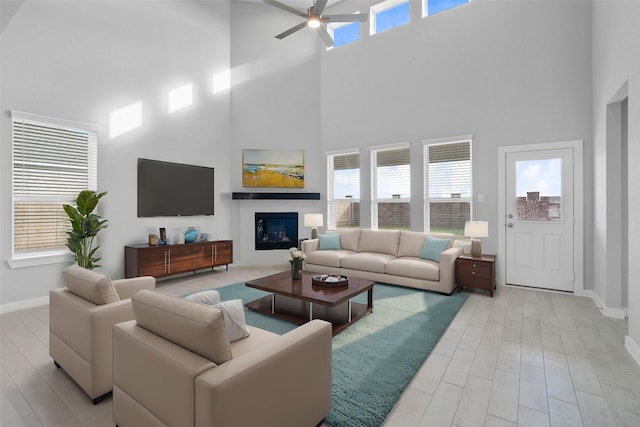 living area with ceiling fan, baseboards, and a towering ceiling