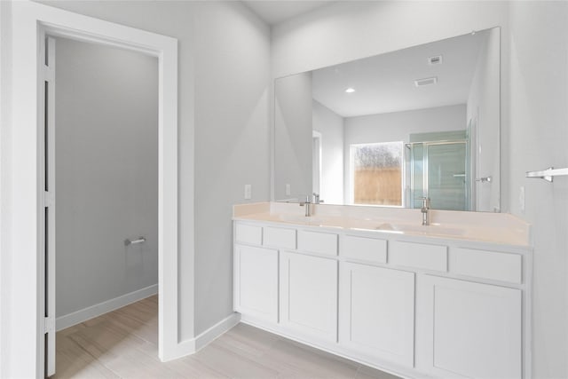bathroom with visible vents, double vanity, baseboards, a sink, and a stall shower