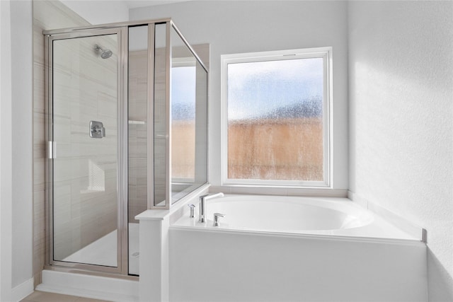 full bath featuring a garden tub, a stall shower, and a healthy amount of sunlight