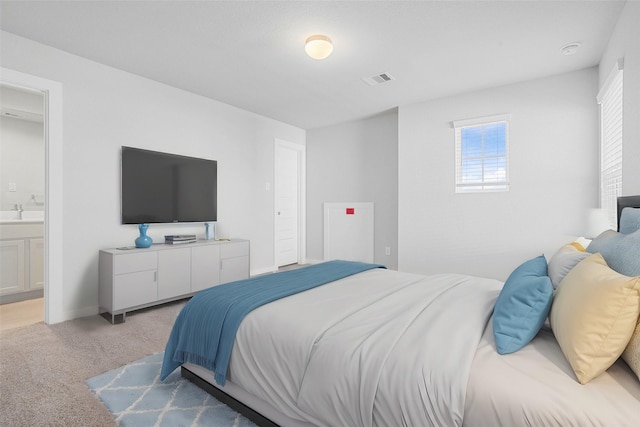 bedroom featuring visible vents, a sink, connected bathroom, and light carpet