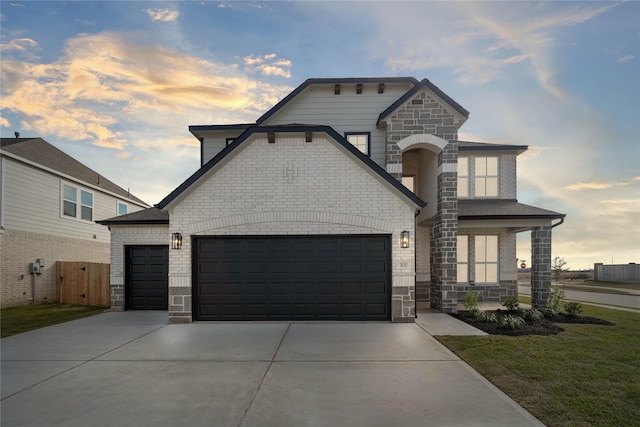 french country style house featuring concrete driveway, brick siding, stone siding, and a garage