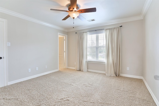 spare room with crown molding, carpet flooring, ceiling fan, baseboards, and visible vents