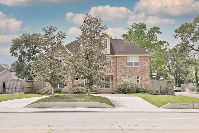 view of front facade featuring a gate, a front lawn, fence, and stone siding