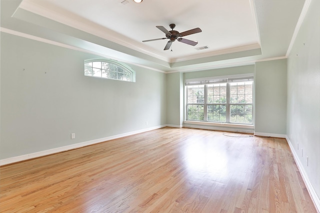 empty room with crown molding, a raised ceiling, ceiling fan, and wood finished floors
