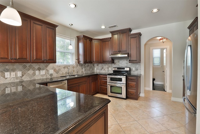 kitchen with visible vents, arched walkways, stainless steel appliances, a sink, and under cabinet range hood
