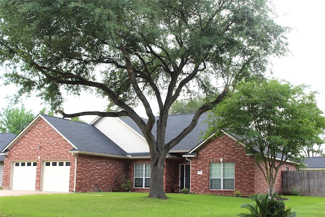 view of front of home with a front yard, roof with shingles, brick siding, fence, and an attached garage