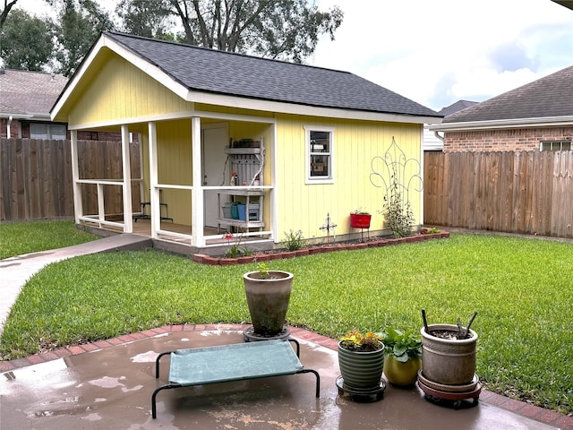 back of property featuring a yard, a fenced backyard, and roof with shingles