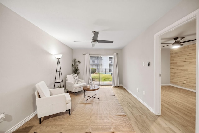 sitting room with baseboards, ceiling fan, and light wood finished floors