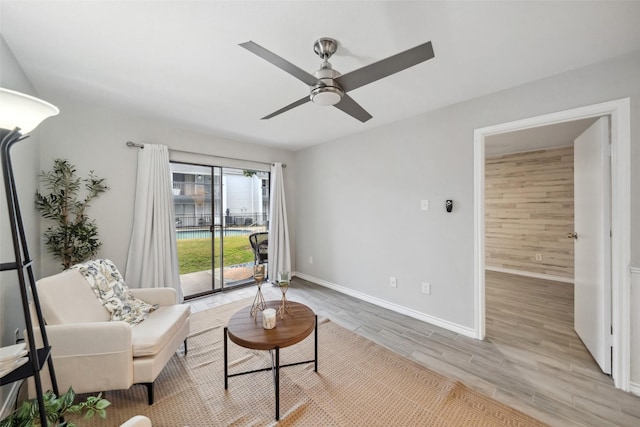 living room featuring a ceiling fan, baseboards, and light wood-style flooring