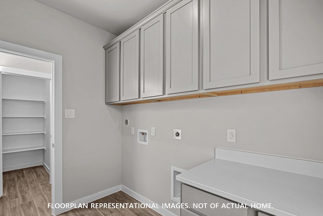 clothes washing area featuring wood finished floors, baseboards, hookup for a washing machine, cabinet space, and hookup for an electric dryer