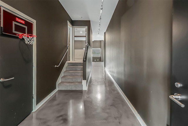 hall featuring concrete flooring and baseboards