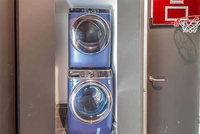 washroom with stacked washer / drying machine, tile patterned floors, and laundry area