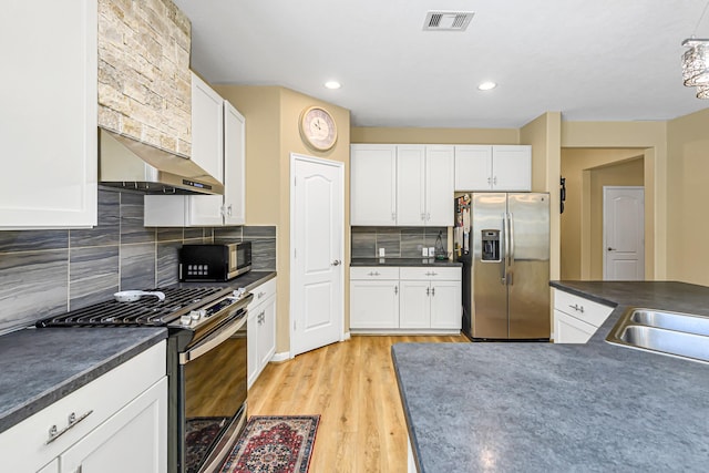 11022 Jacob Crossing Dr, Richmond, TX 77406 - kitchen featuring under cabinet range hood, stainless steel appliances, dark countertops, and white cabinetry