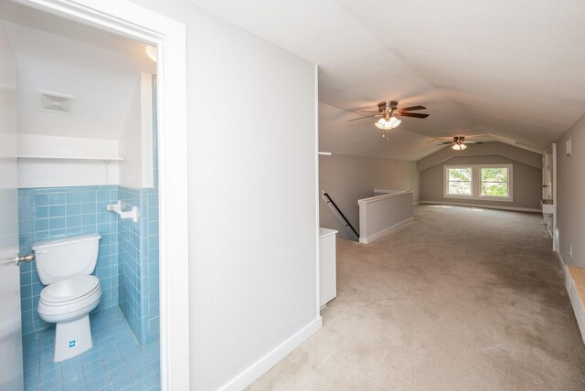 bonus room with ceiling fan, visible vents, wainscoting, vaulted ceiling, and light carpet