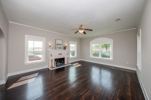 unfurnished living room featuring arched walkways, a wealth of natural light, dark wood-style flooring, and visible vents