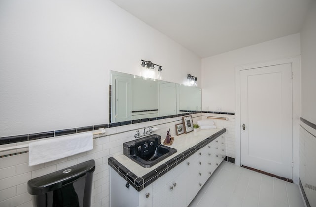 bathroom featuring a sink, tile walls, a wainscoted wall, and tile patterned floors
