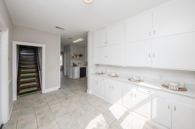 kitchen featuring light countertops, baseboards, white cabinets, and visible vents