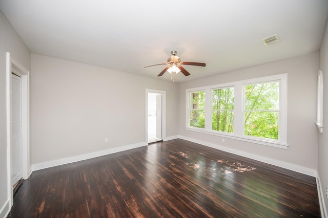 spare room with baseboards, a ceiling fan, dark wood-style floors, and visible vents