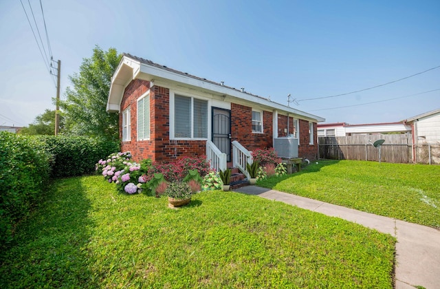 view of front of house with brick siding, fence, a front yard, and entry steps