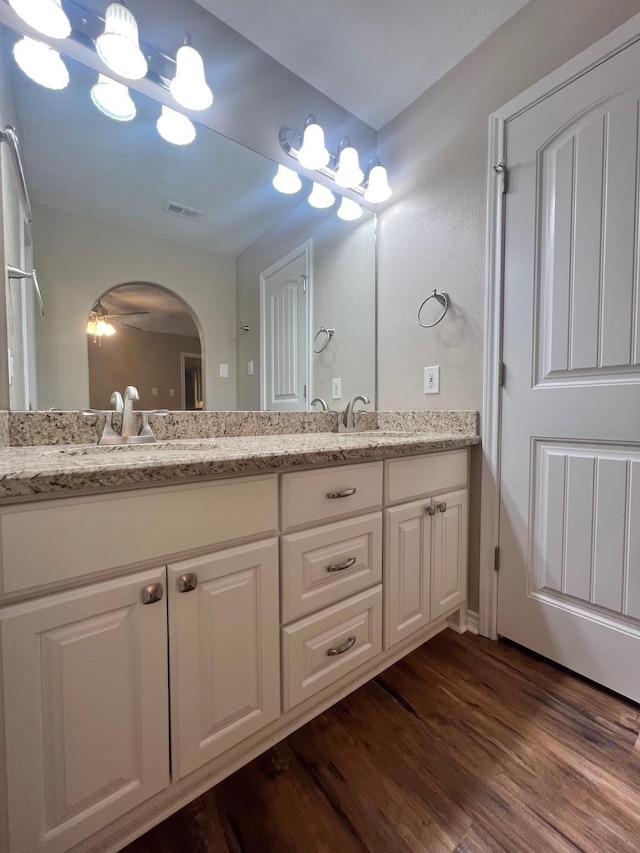 bathroom featuring double vanity, a sink, visible vents, and wood finished floors