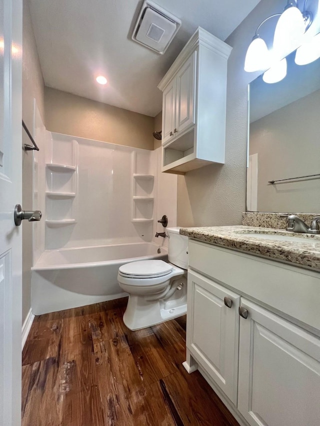 bathroom with visible vents, vanity, wood finished floors, toilet, and  shower combination