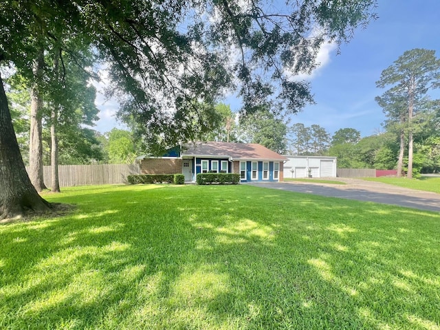 single story home featuring fence, a front yard, and a detached garage
