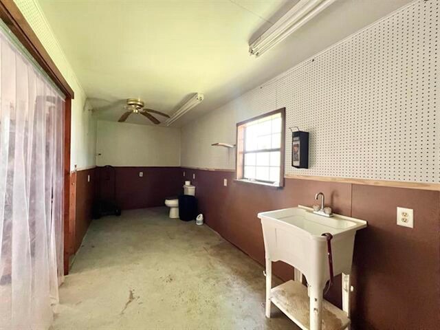 interior space featuring a ceiling fan and a wainscoted wall