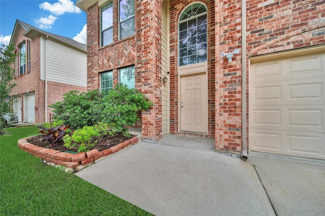 property entrance featuring brick siding, a garage, and concrete driveway