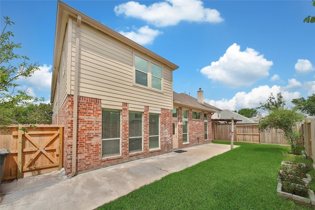 back of property with a lawn, a patio, brick siding, and a fenced backyard