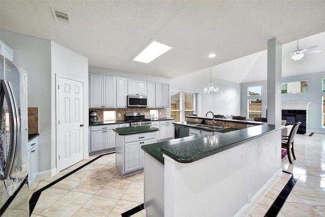 kitchen with a large island, visible vents, appliances with stainless steel finishes, a sink, and baseboards