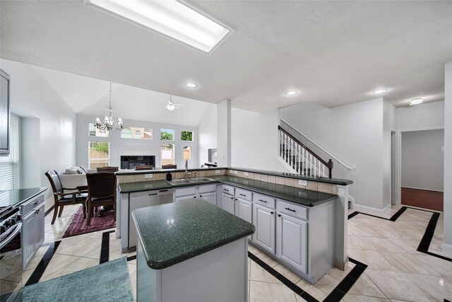 kitchen with a sink, a center island, open floor plan, baseboards, and stainless steel dishwasher
