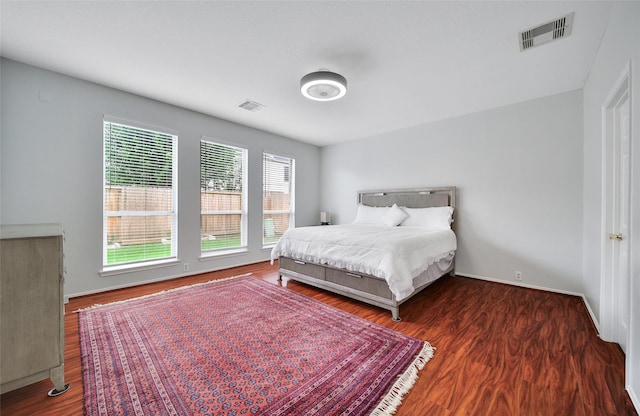 bedroom with visible vents, baseboards, and wood finished floors